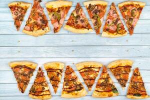 Lots of delicious triangular pizza slices on a blue wooden background photo