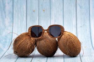 three whole coconuts and wooden glasses on a blue wooden background photo