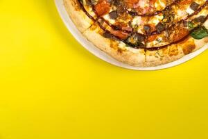 Delicious large pizza with bacon and spinach on a yellow background photo