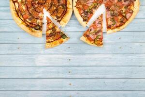 Two different delicious big pizzas on a blue wooden background photo