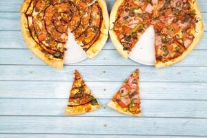 dos diferente delicioso grande pizzas en un azul de madera antecedentes foto