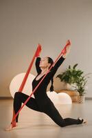 Girl in black doing fitness with red ribbons indoors photo