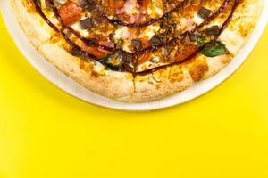 Delicious large pizza with bacon and spinach on a yellow background photo