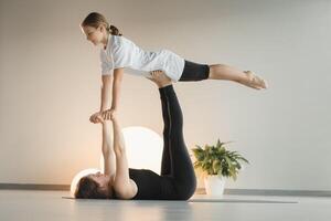 Mom and teenage daughter do gymnastics together in the fitness room. A woman and a girl train in the gym photo