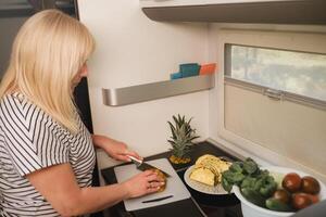 a woman cooking food in the kitchen inside a motorhome, the interior of a motorhome photo