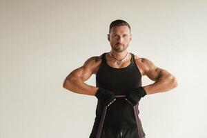 A man in black sportswear is engaged in strength fitness using a rubber loop indoors photo