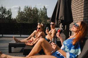 A happy family in swimsuits sunbathe in summer on their terrace on sun beds photo