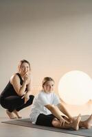 Mom and teenage daughter do gymnastics together in the fitness room. A woman and a girl train in the gym photo