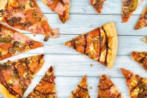 Lots of delicious triangular pizza slices on a blue wooden background photo