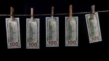 Dollars dry on a clothespin rope on a black background. The financial concept of the dollar. Hundred dollar bill on a rope. Money laundering concept. video