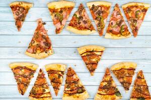 Lots of delicious triangular pizza slices on a blue wooden background photo