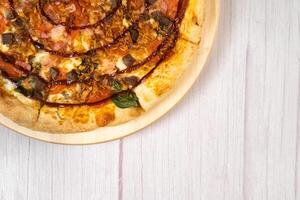 Delicious large pizza with bacon and spinach on a light wooden background photo