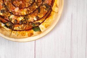 Delicious large pizza with bacon and spinach on a light wooden background photo