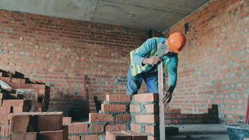 un constructor en un sitio de construcción pone ladrillos en la casa. Conducto de ventilación de ladrillo constructor. video