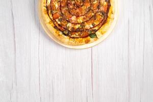 Delicious large pizza with bacon and spinach on a light wooden background photo