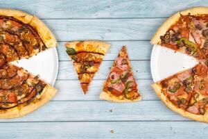 dos diferente delicioso grande pizzas en un azul de madera antecedentes foto