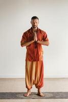 un hombre en un naranja traje lo hace yoga en un aptitud habitación. el concepto de salud foto