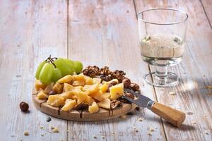 Cheese plate with a variety of snacks on a wooden table with a glass of wine photo