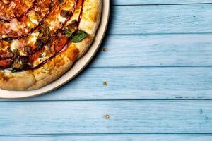 Delicious large pizza with bacon and spinach on a blue wooden background photo