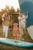 the family is resting next to their mobile home. Dad, mom and daughter play on sup boards with water pistols near the motorhome photo