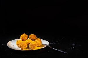 cheese balls with garlic and dill inside for a snack in a plate on a black background photo