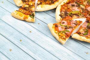 Two different delicious big pizzas on a blue wooden background photo