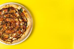 Delicious large pizza with bacon and spinach on a yellow background photo