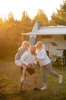 Happy parents with their child playing with a ball near their mobile home in the woods photo
