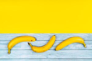 amarillo bananas mentira en un azul de madera antecedentes y un amarillo antecedentes foto