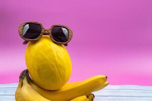 An assortment of yellow fruits and glasses lies on a pink background photo