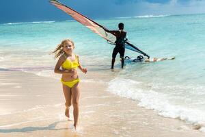 a little girl runs along the beach of the tropical island of Mauritius in the Indian Ocean photo