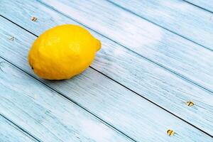 A whole yellow lemon lies on a blue wooden background photo