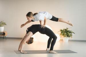 Mom and teenage daughter do gymnastics together in the fitness room. A woman and a girl train in the gym photo