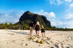 un familia de Tres en negro ropa en el blanco playa de le morne en el isla de mauricio foto