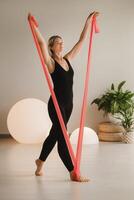 Girl in black doing fitness with red ribbons indoors photo