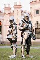 dos caballeros en armadura en el antecedentes de el medieval kossovsky castillo.a medieval concepto.metálico textura foto