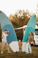 the family is resting next to their mobile home. Dad, mom and daughter play with sup boards and water pistols near a mobile home photo
