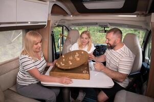 A family of three is playing a board game while sitting in a motorhome photo