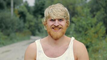 porträtt av en ryska man från de by. en man med en gul skägg och gul tänder i en t-shirt. video