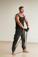 A man in black sportswear is engaged in strength fitness using a rubber loop indoors photo