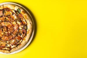 Delicious large pizza with bacon and spinach on a yellow background photo