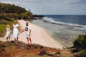 a family in white with three people looks into the distance of Gris Gris beach on the island of Mauritius. The family looks at the beautiful nature of the island of Mauritius and the Indian ocean photo