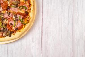 Delicious large pizza with veal and mushrooms on a light wooden background photo