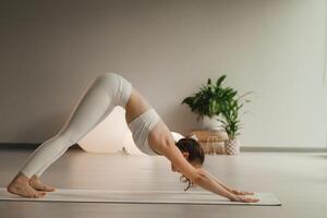 A girl in white clothes does yoga on a mat indoors photo