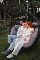 A happy family is sitting in a hammock on the lawn near the house photo