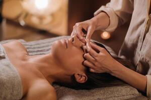 A cosmetologist girl does a facial and neck massage to a girl in the office for skin elasticity photo