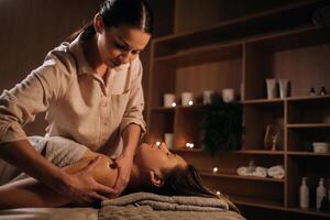 un masajista da un cuerpo masaje a un mujer en un spa centro. un profesional masajista masajes el hombro de un niña acostado en un spa centrar foto
