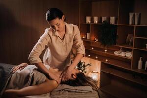 A masseuse gives a body massage to a woman in a spa center. A professional masseur massages the shoulder of a girl lying in a spa center photo