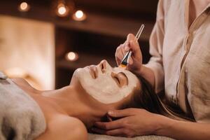 A cosmetologist makes a mask for a woman's face to rejuvenate the skin. Cosmetology photo