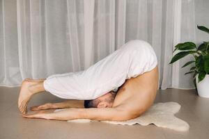 a man with a bare torso does yoga in a fitness room. the concept of a healthy lifestyle photo